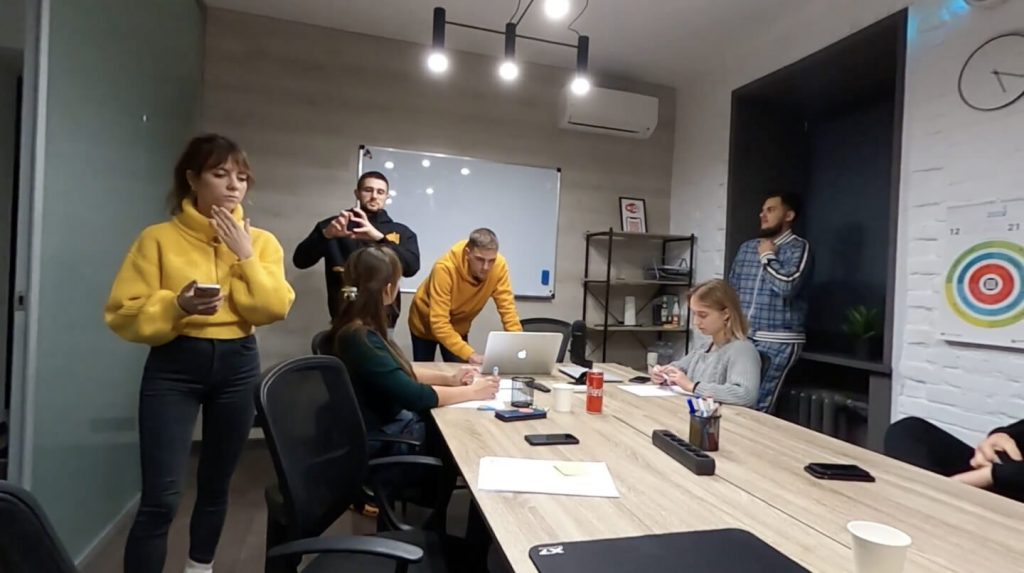 Project team at a kickoff meeting around a conference table with a laptop, notes and a whiteboard