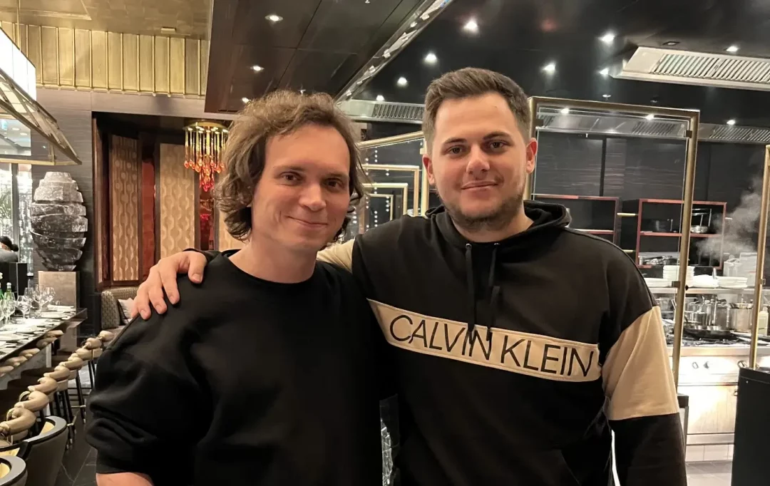 The ELLE Oʻzbekiston and Spaceberry Studio CEOs posing arm in arm in a restaurant with an open kitchen